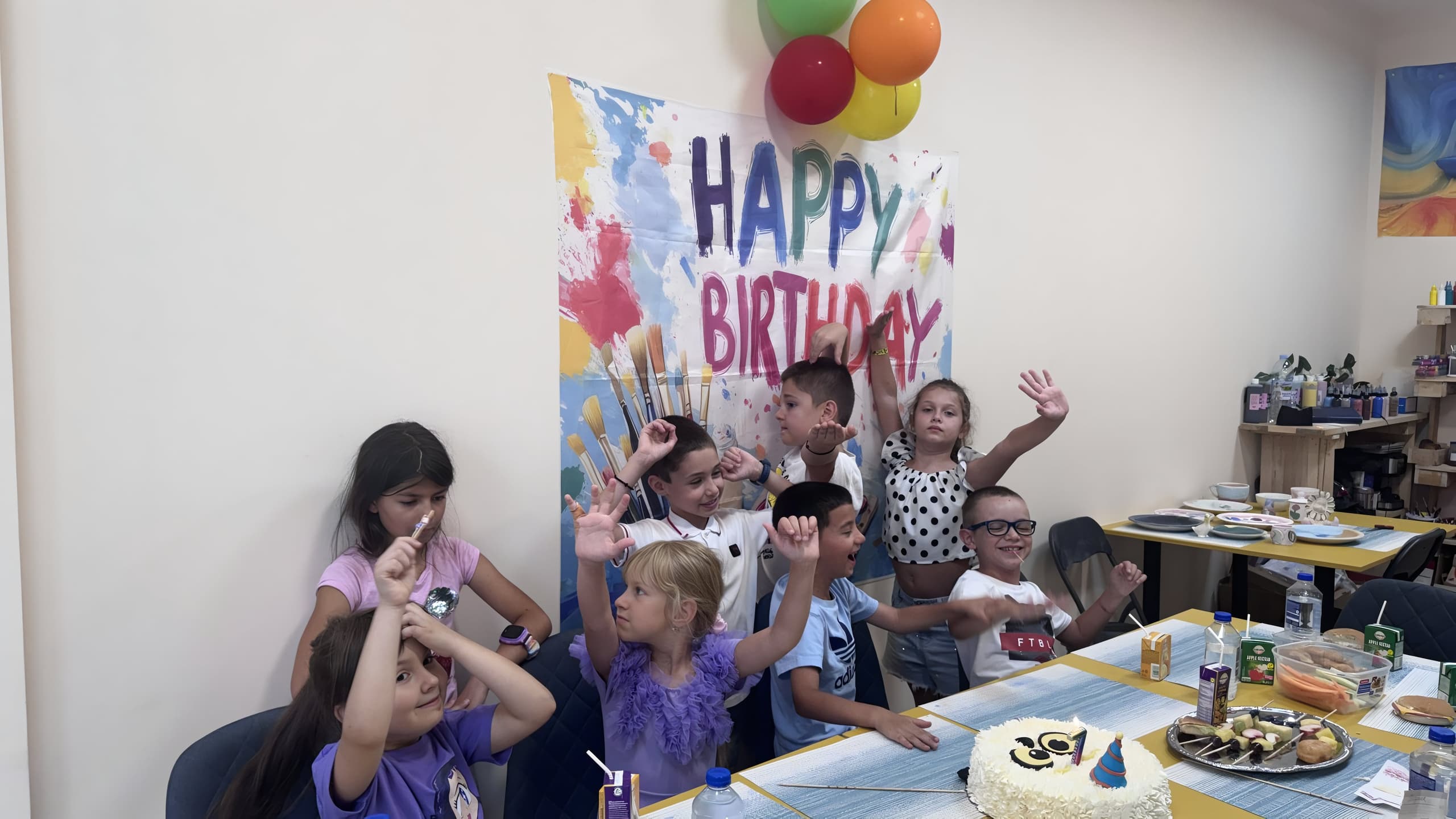 Деца празнуват рожден ден в ателието — банер Happy Birthday, балони и торта